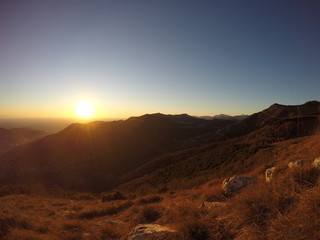 Fiery sunset from mountain pick with thin glazes in the sky evening. Fall season. Orobie alps. The summit of Mount Rena. Bergamo Italy. 
