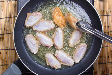 Chef frying chicken wings in pan
