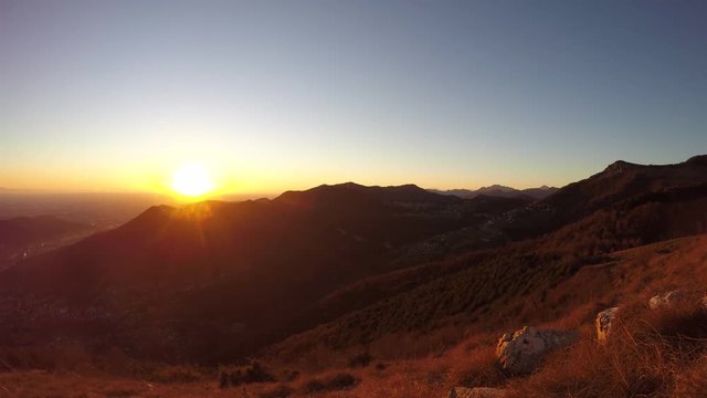 Time lapse fiery sunset from mountain pick with thin glazes in the sky evening. Fall season. Orobie alps. Rena pick. Bergamo Italy. In the distance the Monviso.
