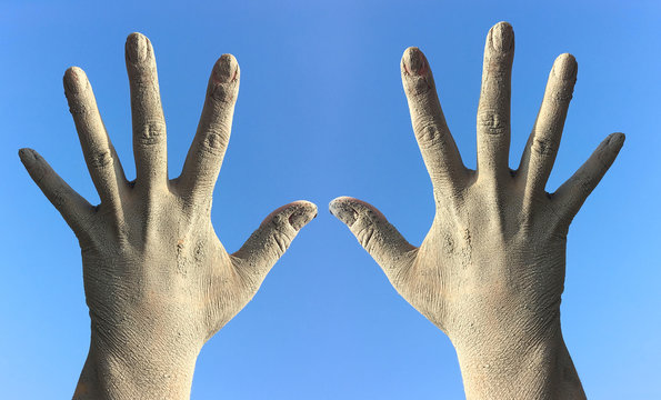 Two female hands in the dirt and dust from the splayed fingers a