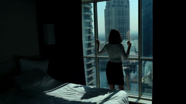 Young businesswoman dancing by window in hotel room, super slow motion 240fps

