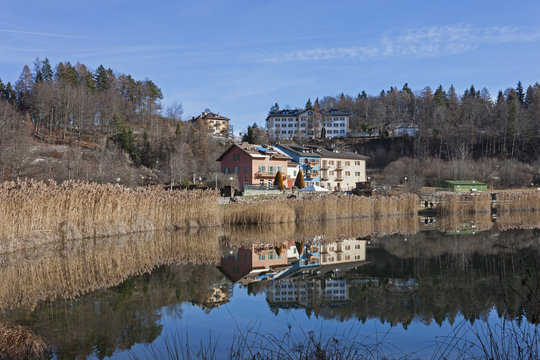 Reflected in blue waters of Lavarone Lake, on the Alpe Cimbra