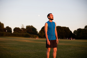 Young athletic man taking a post run break at sunset in the park