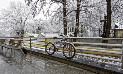 A cycle parked on the side of a road against a fence