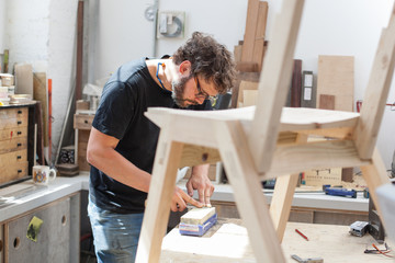 Furniture maker sharpening a chisel in his workshop