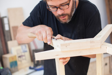 Close up of a furniture maker chiselling a chair joint