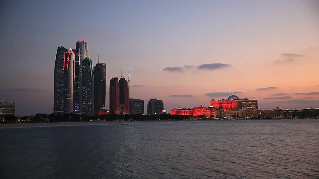 Abu Dhabi skyline at sunset with skyscrapers lit up for the 43rd National day