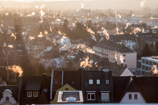 Rauchende Schornsteine &uuml;ber den D&auml;chern einer Stadt