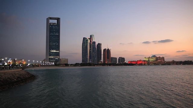Abu Dhabi skyline at sunset with skyscrapers lit up for the 43rd National day