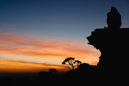 Man, stone and trees silhouettes at sunrise in Brazil