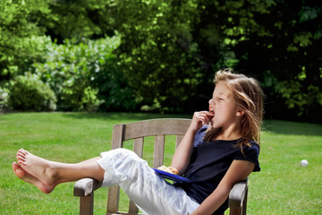 Young girl relaxes in the garden eating her afternoon snack