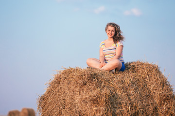 Naklejka na ściany i meble Beautiful Plus Size Young Woman In Shirt Sit Near Hay Bales In Summer