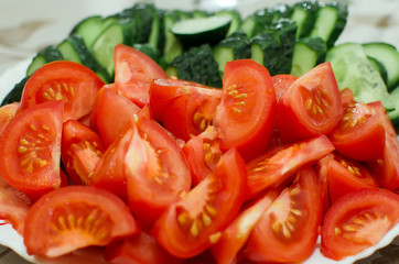 sliced tomatoes and cucumbers lie on a plate, close-up