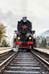 Rare steam train locomotive preparing for departure from picturesque railway station in the Carpathian mountains, vertical image