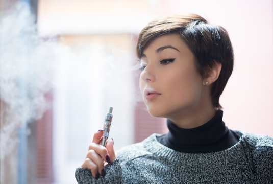 Young pretty woman smoking electronic cigarette