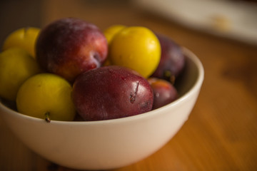 Naklejka na ściany i meble Purple and yellow plums in bowl
