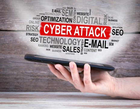 Cyber Attack concept. Tablet computer in the hand. Old wooden background.