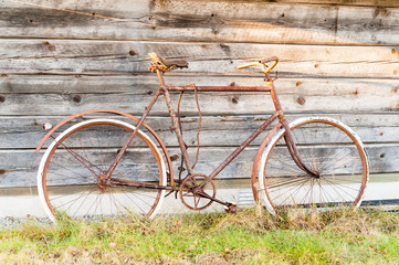 Fototapeta na wymiar Old and rusty bike abandoned outside a wooden cabin a long time ago.
