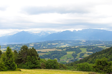Obraz premium Panoramic view of Swiss Alps near Geneva, Switzerland. Farmhouses and hilly countryside on a cloudy day in summer.
