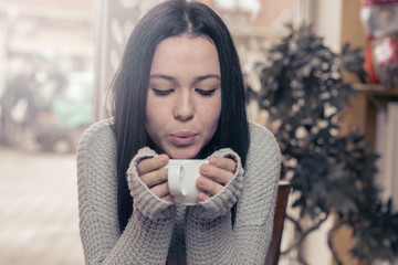 Young brunette Caucasian woman is drinking tea at a bar.