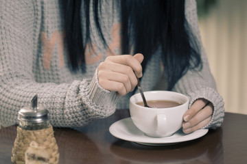 Young brunette Caucasian woman is drinking tea at a bar.