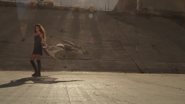 Beautiful girl with the waving fabric positing, dancing, running, walking in the LA River. Industrial area fashion videoshoot.