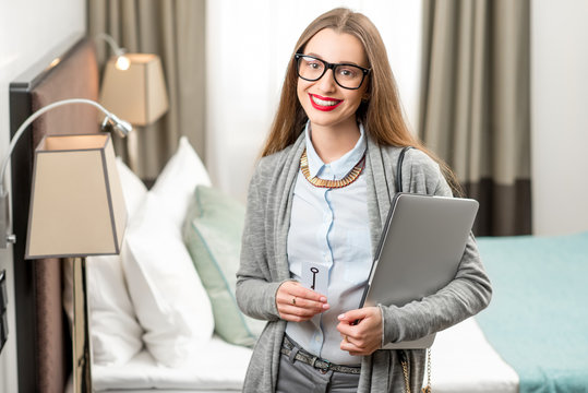 Portrait of a happy business woman standing with laptop in the luxury hotel room. Staying at the hotel during the business trip