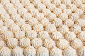 Fresh delicious vanilla meringue background texture. Rows of white meringue cookies on a baking...