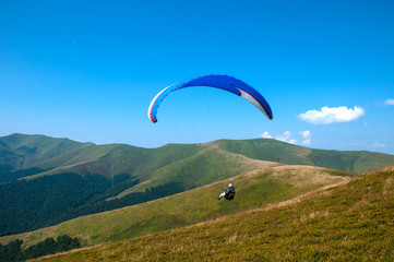Paraglider flies paraglider over the tops of the mountains in summer sunny day. Karpaty, Ukraine