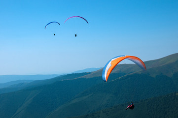 Paraglider flies paraglider over the tops of the mountains in summer sunny day. Karpaty, Ukraine
