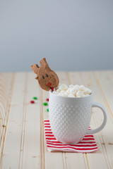 A mug with hot chocolate and marshmallows decorated with a chocolate reindeer shaped marshmallow. Copy space. 