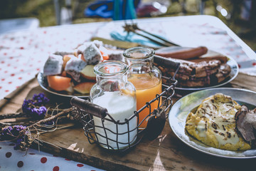 Various breakfast table with fruits egg and sausage, orange juice and milk