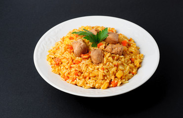 A delicious pilaf wit meat in a plate on dark background