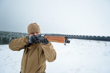 Hunter man dressed in camouflage clothing standing in the winter