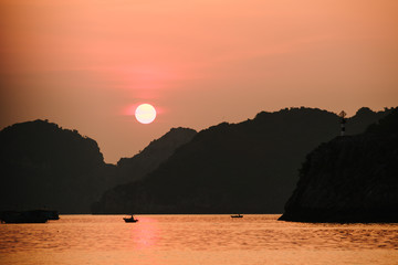 Asian fishing boats at sunset on a background of mountains.