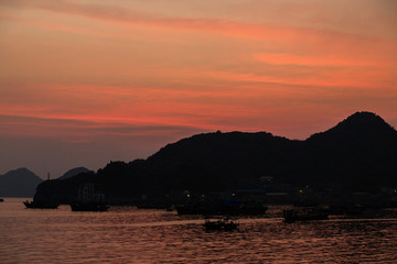 Asian fishing boats at sunset on a background of mountains.