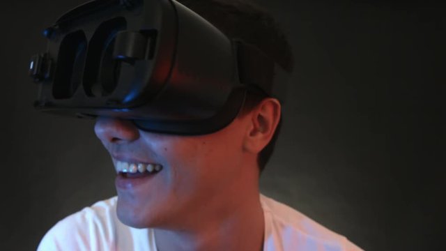 Close-up shot of a funny looking young man wearing VR Headset experiencing virtual reality. Captured with Blackmagic Production Camera 4K with RAW settings.