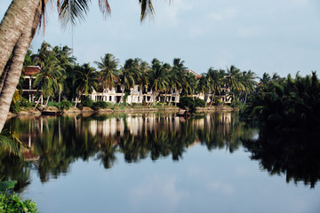 Houses in territory with palm trees, river reflecting on the wat
