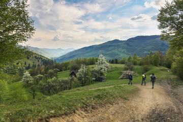 three hikers walking down to the village after long mountain hike in spring