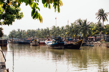 small dirty river with boats and bridges in Asia