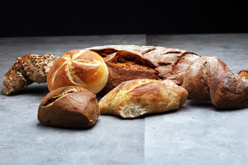 Different kinds of bread rolls on black board from above. Kitchen or bakery poster design.