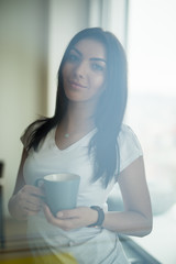 Woman with coffee cup in rest room at office