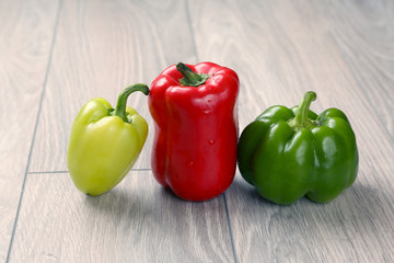 three colored sweet pepper on a wooden table