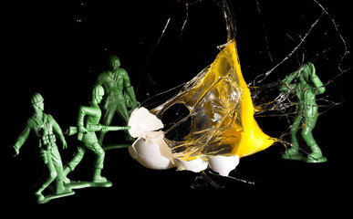 Exploding high speed egg with toy army men. Concept for war and death