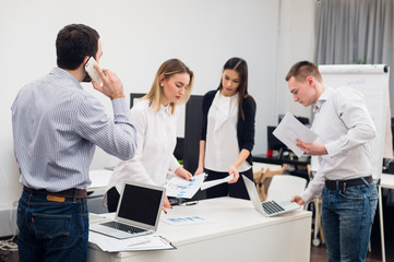 Obraz premium Young business people sitting in office during meeting and discussing with paperwork using laptops