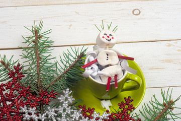 Christmas card with fun marshmallow snowman in green cup, tree