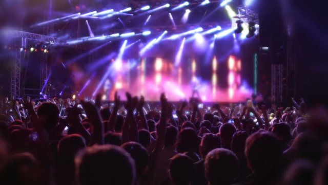 People jumping and waving hands, enjoying favorite music and songs at concert