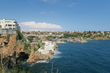 Obraz premium The Cliffs of Antalya with a Small Cave and the Stunning Oldtown Harbour