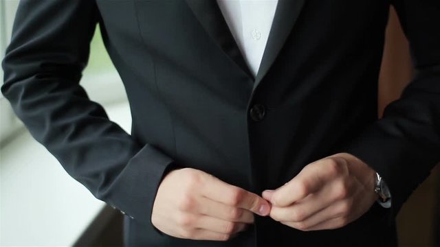 Stylish man dressed in suit buttoning jacket close up. Male hands of confident gentleman adjust outfit preparing for formal evening. Image establishment leadership lifestyle masculinity style success 
