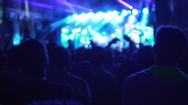 People watching performance on illuminated stage, enjoying good music at concert